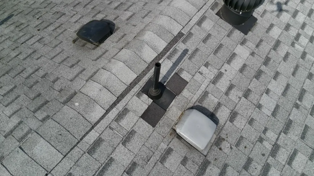 Close-up of asphalt shingles with a vent and pipe flashing, common sources of roof leaks